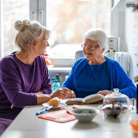 Pflegefachkraft mit älterer Dame sitzend am Tisch